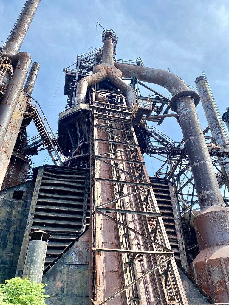 Old industrial towers and rusty pipes viewed from below.