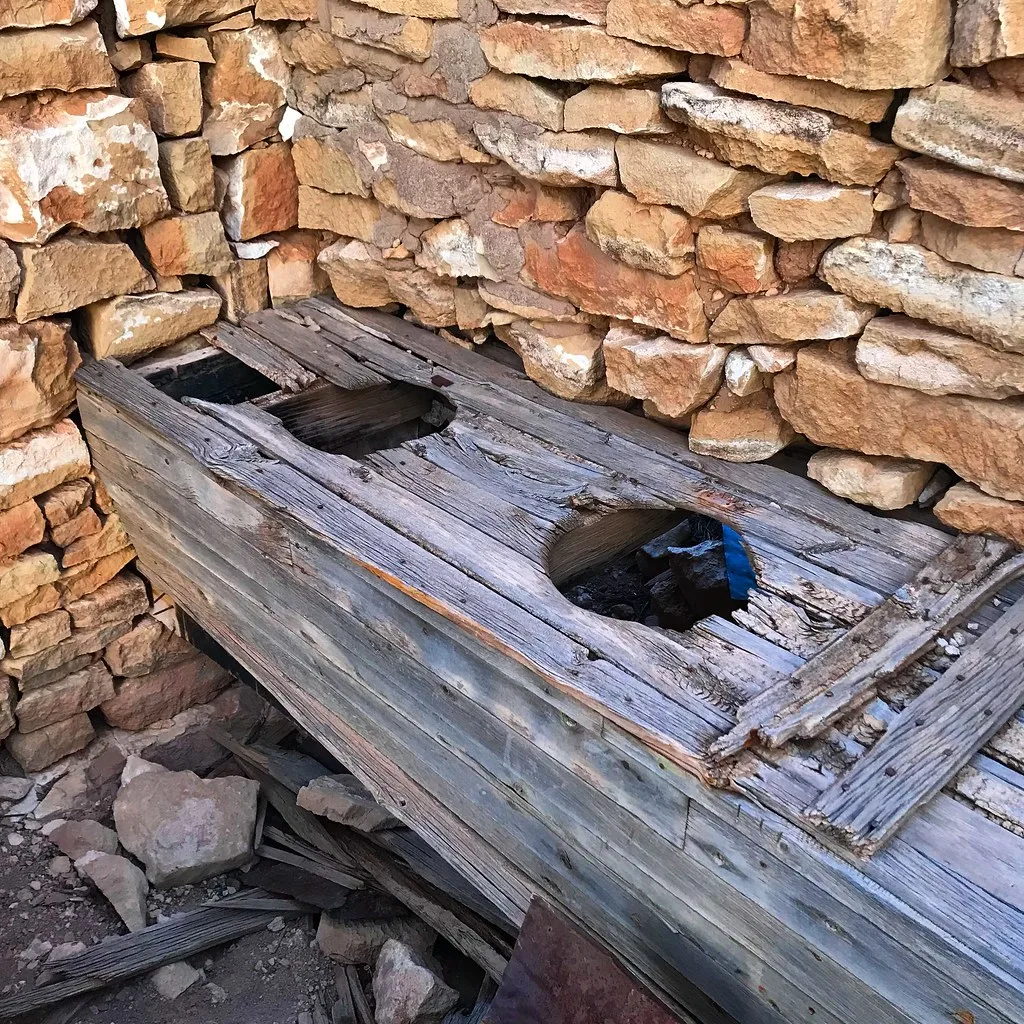 Dilapidated old wooden latrines against stone walls.