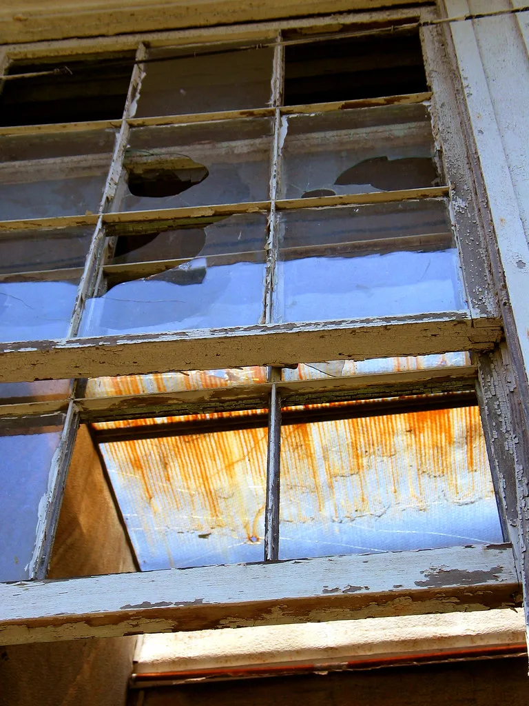 Old window with broken panes and a peeling frame.