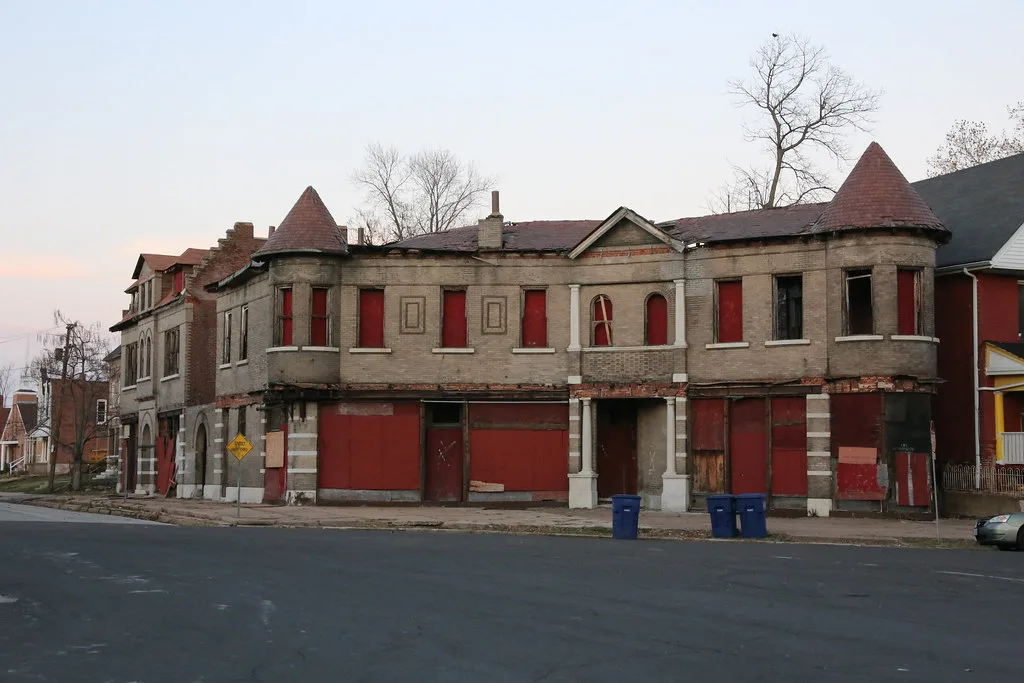 Former row of shops with corner turrets and windows sealed with red boards.