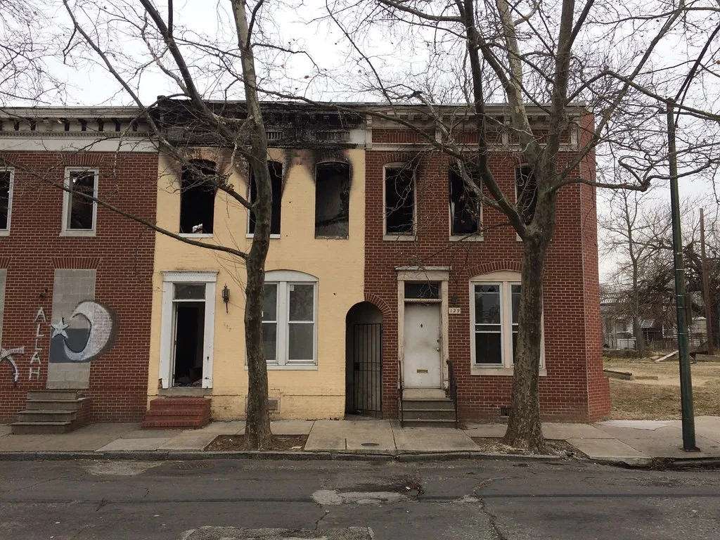 Brick row houses with empty windows and a fire-blackened upper floor.