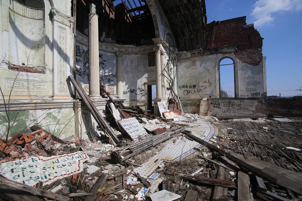 Ruined chapel interior with columns, an open roof and debris on the floor.