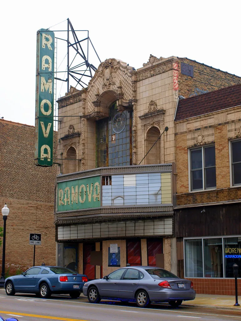 Old cinema with boarded entrances beneath a Ramova sign.