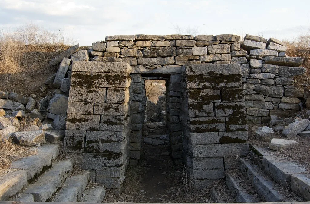 Narrow passage through a stone ruin with fallen blocks.