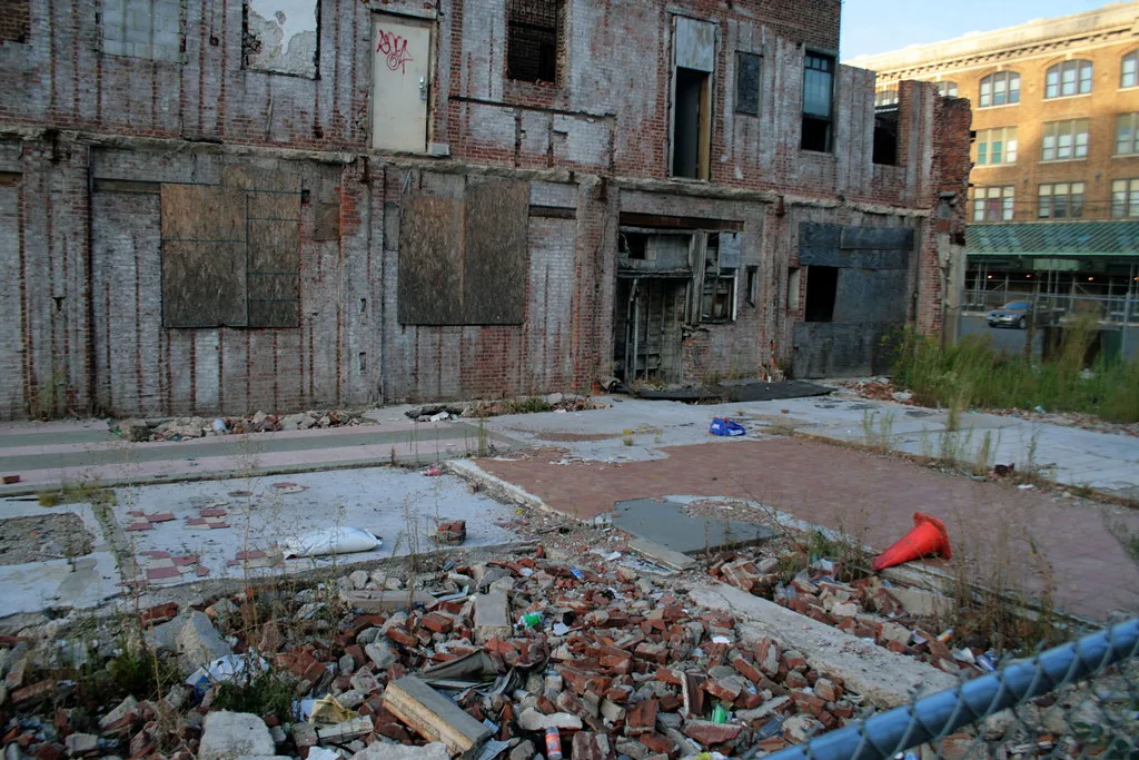 Deteriorated old brick building behind foundations and rubble.