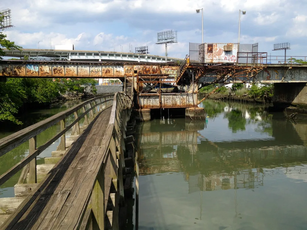 Old rusty metal bridge with a graffiti-covered cabin above the water.