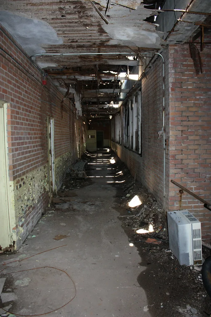 Long brick corridor with a collapsed ceiling and debris on the floor.