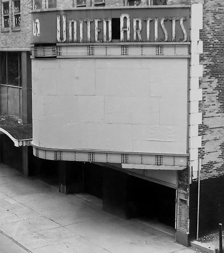 Marquise vide et entrée fermée d’un ancien cinéma, en noir et blanc.