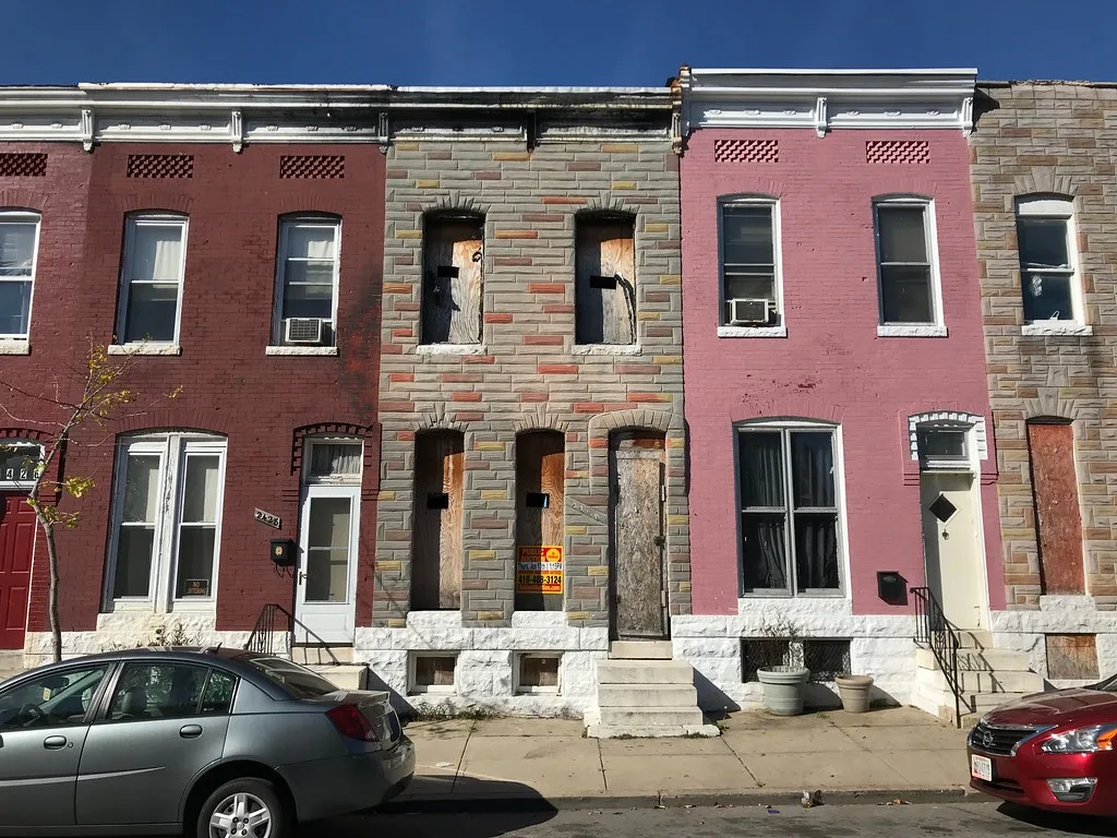 Boarded rowhouse between colored facades.
