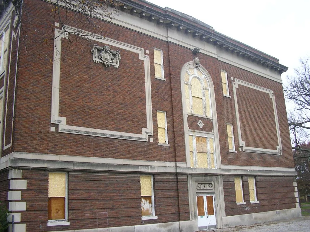 Façade en briques à décors clairs et fenêtres condamnées.