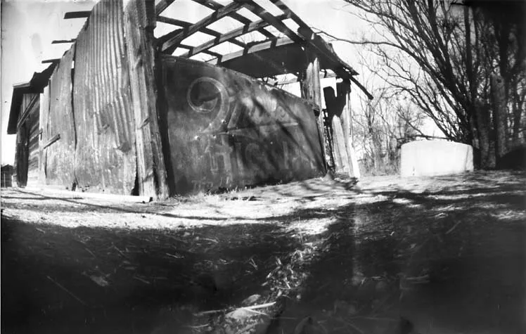 Ancienne remise ruinée abritant une citerne, en noir et blanc.
