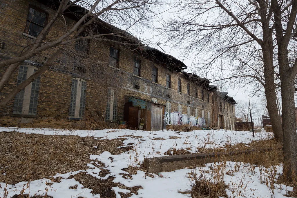 Old brick industrial building with deteriorated openings, in the snow.
