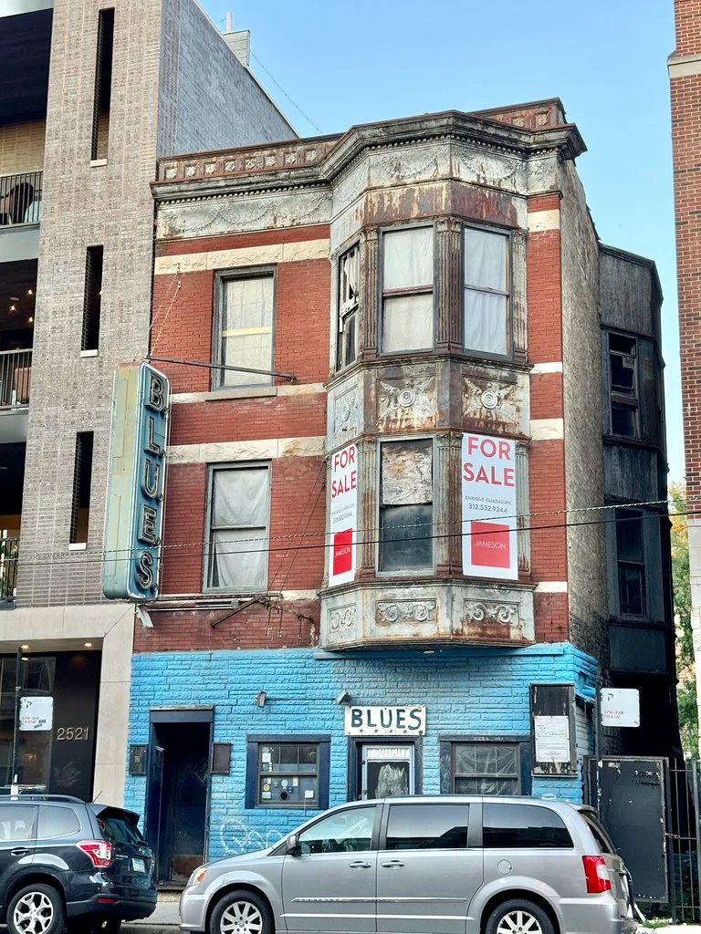 Brick facade and blue ground floor of a closed former shop.