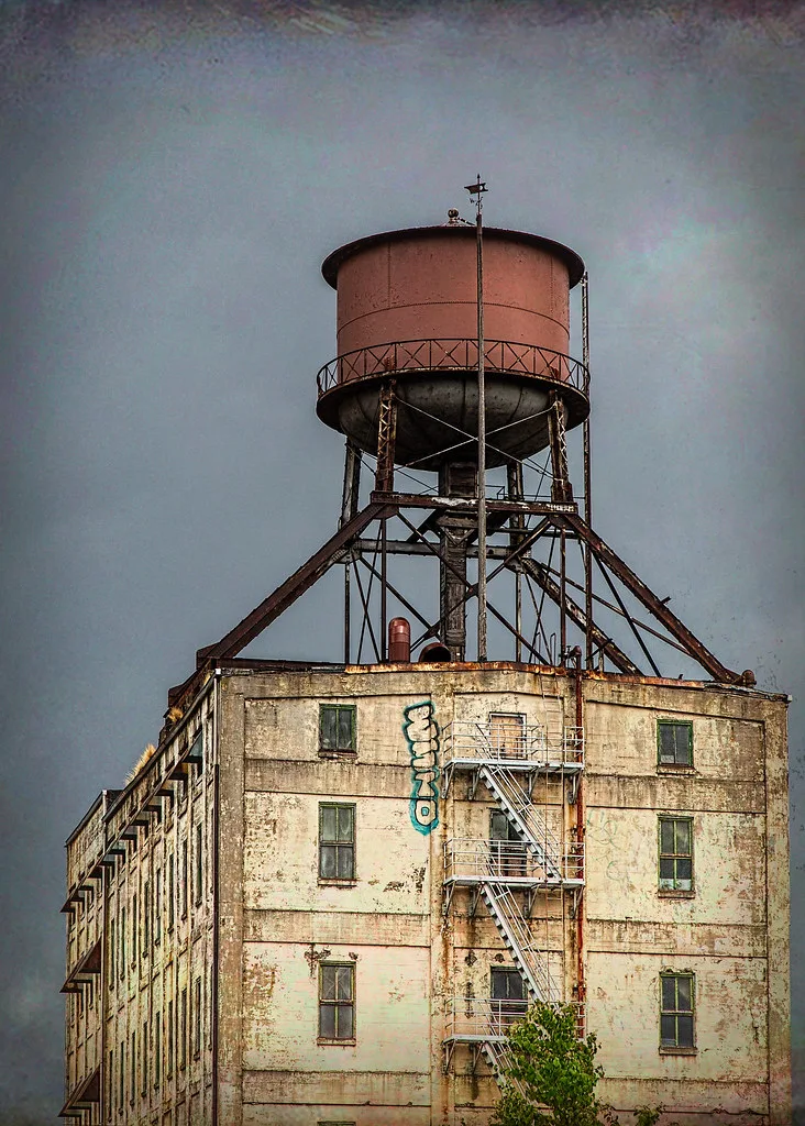 Old industrial building topped by a rusty metal water tank.