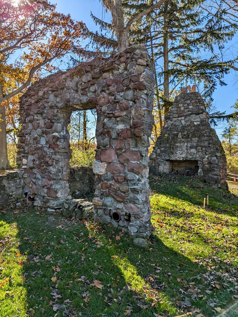 Ruines de pierre d’une maison avec ouverture de fenêtre et grande cheminée parmi les arbres d’automne.