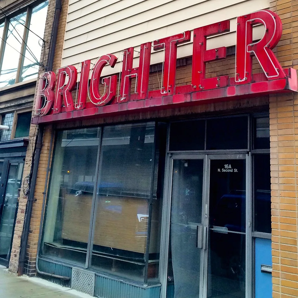 Closed old storefront beneath a red Brighter sign.