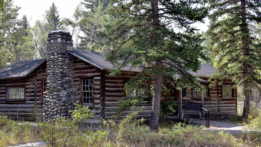 Maud Noble's log cabin with a stone chimney among trees.