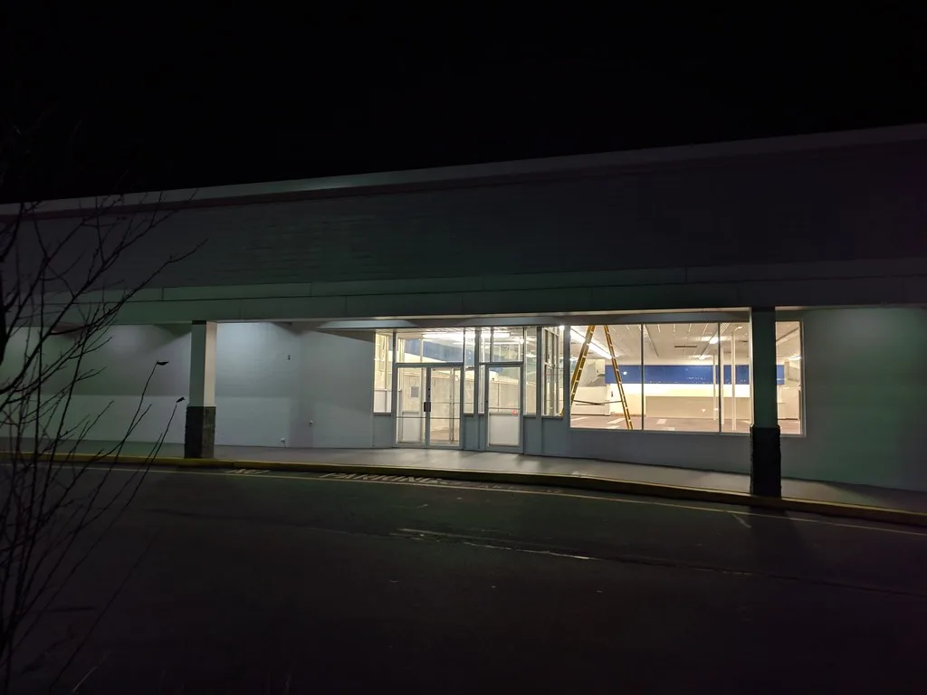 Devanture éclairée d’un ancien commerce vide, vue de nuit.