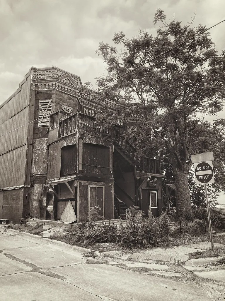 Abandoned corner building with dilapidated wooden balconies and sealed openings.