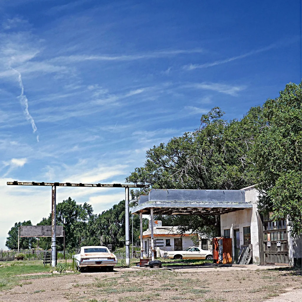 Derelict old service station with rusty pumps and old cars.