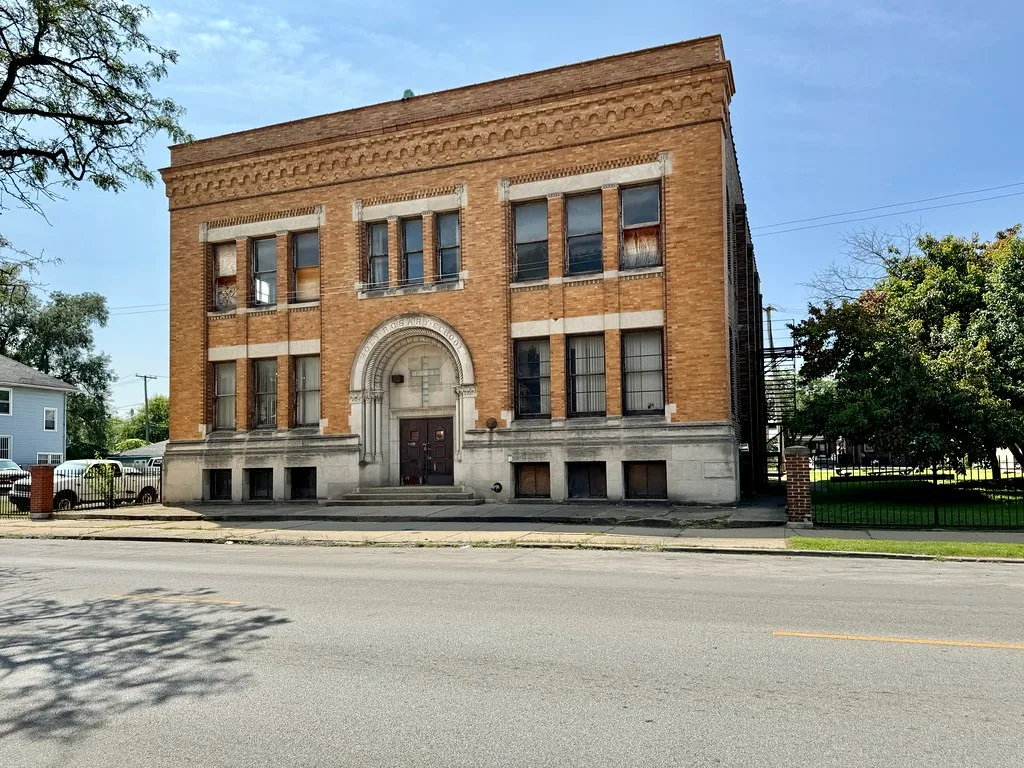 Ancienne école en briques aux fenêtres partiellement condamnées.