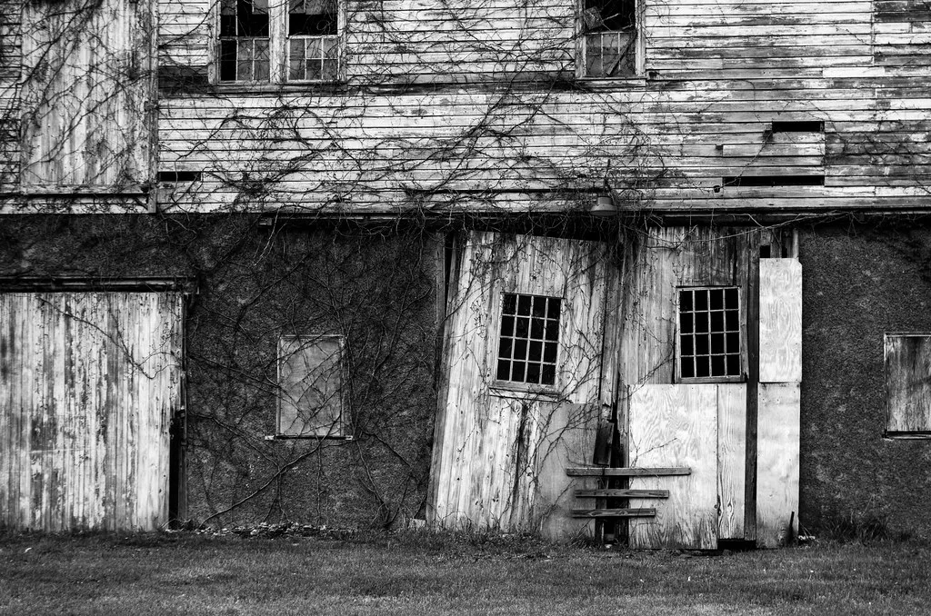 Dilapidated wooden facade with broken panes photographed in black and white.