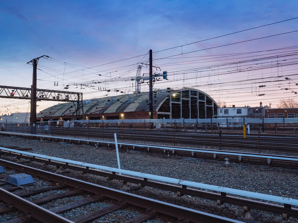 Vaulted roof of ULine Arena behind railway tracks.
