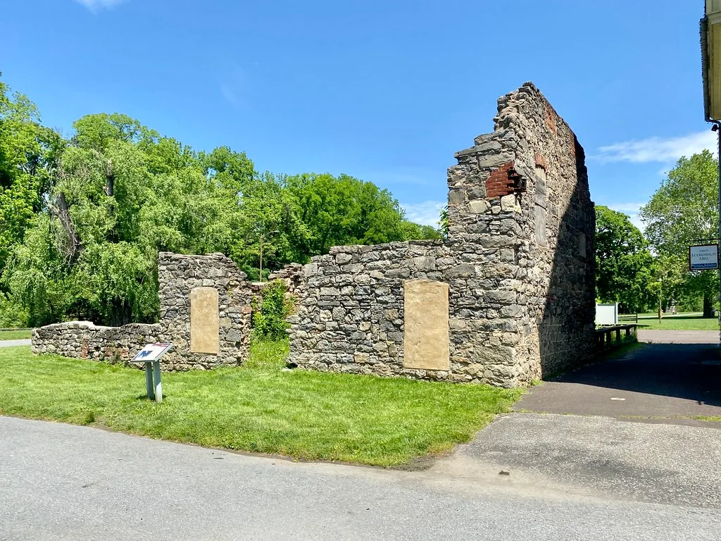 Murs de pierre en ruine sans toiture au bord d’une pelouse.