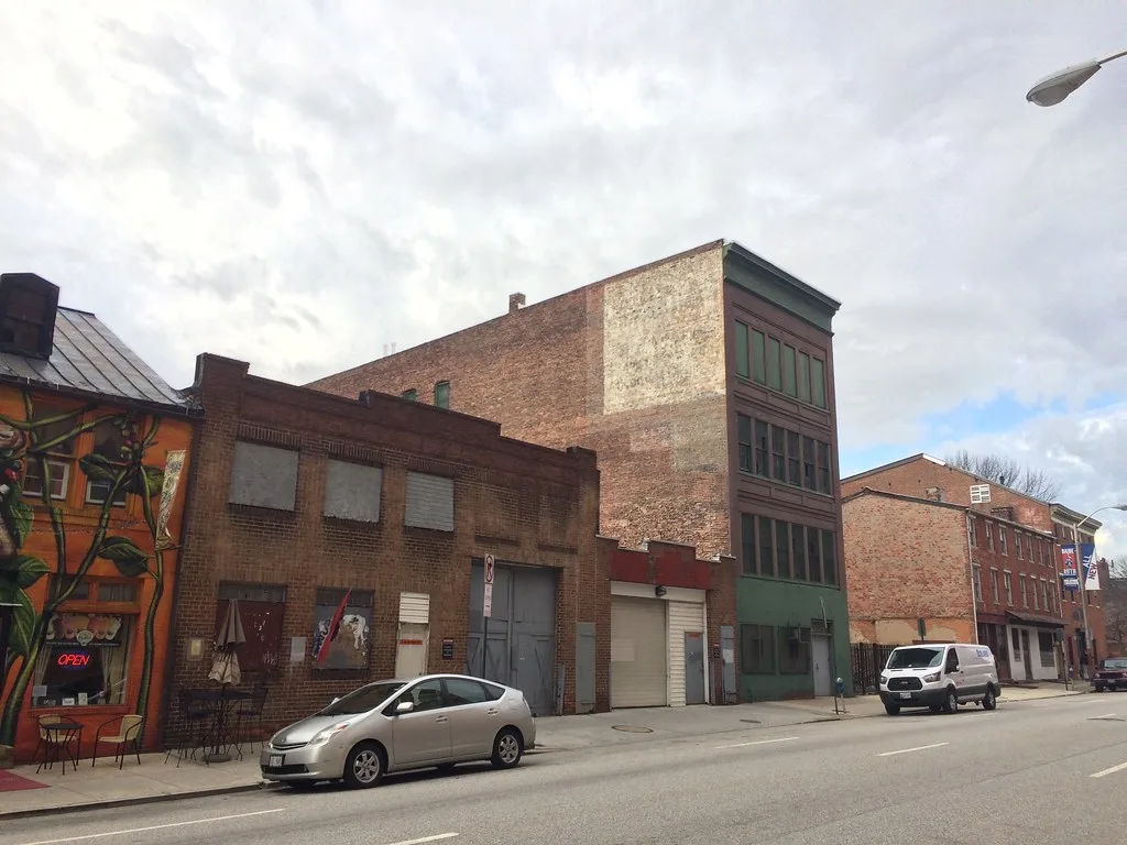 Ancien immeuble industriel de briques aux baies condamnées dans une rue.