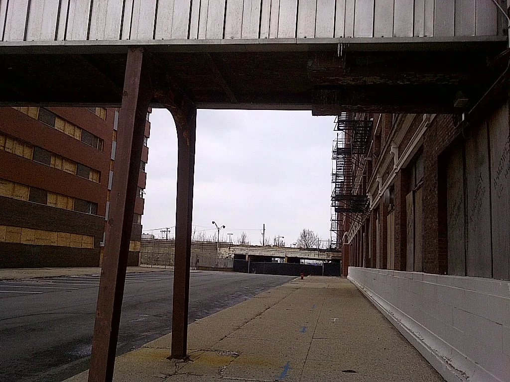Bâtiments industriels aux baies condamnées reliés par une passerelle couverte.