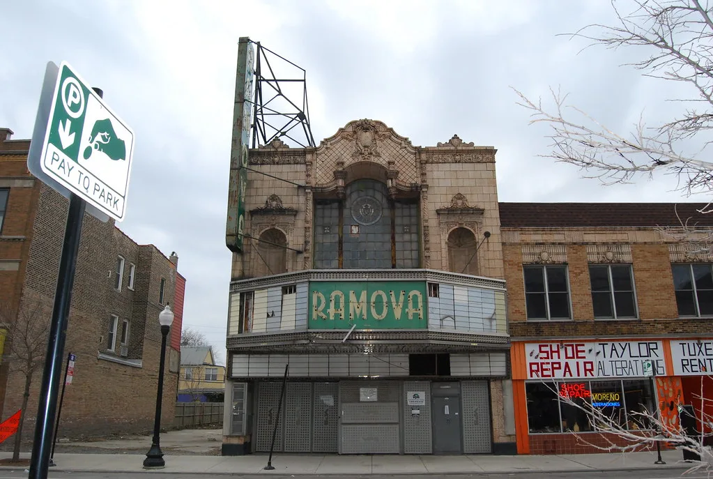 Abandoned former Ramova cinema with an ornate facade and deteriorated marquee, sealed by metal panels.