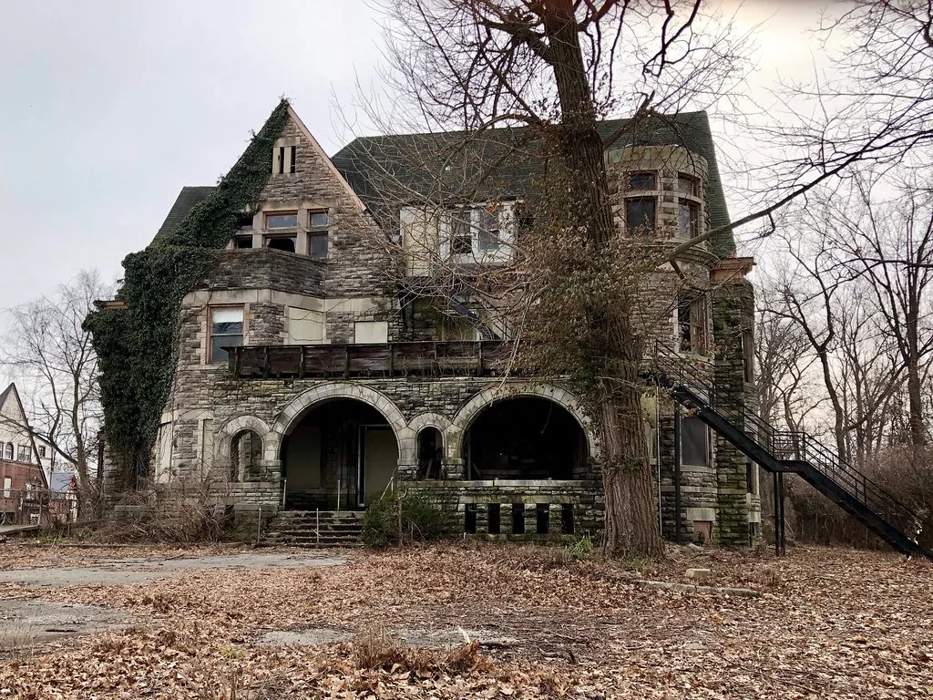 Old stone house with broken windows and an arched porch.