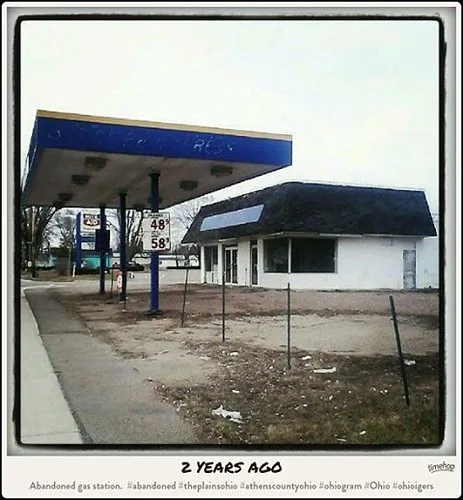 Old filling station with a blue canopy and white building.