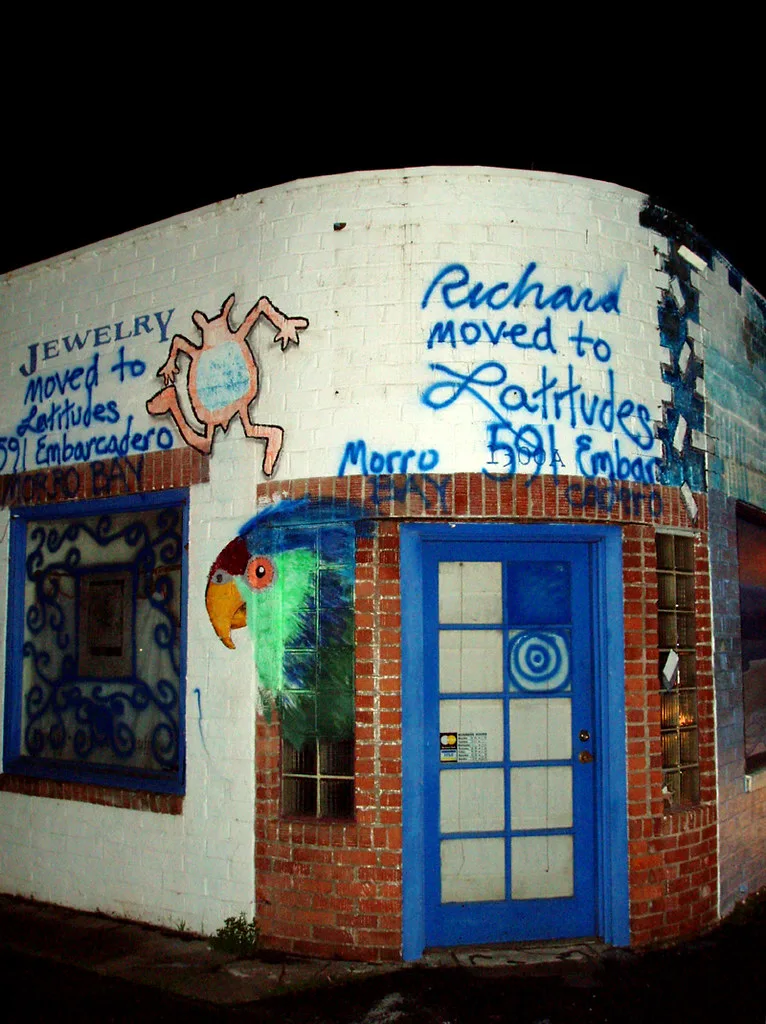 Rounded facade of a former gas station with a blue door and painted lettering.