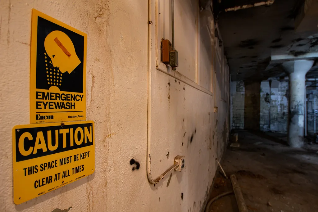 Old yellow safety signs in a dilapidated industrial basement.