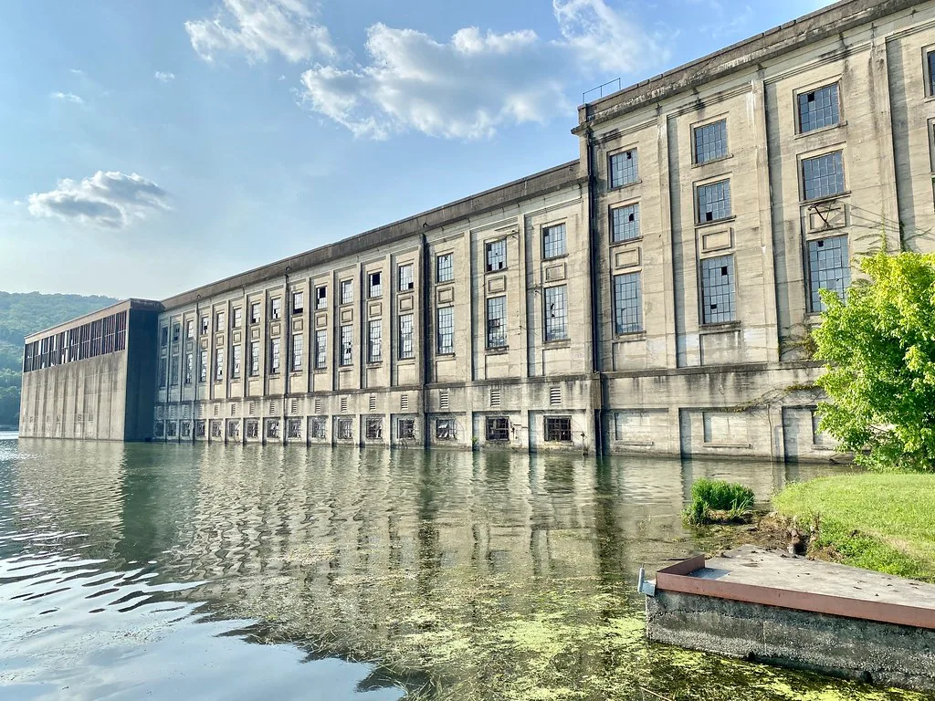 Old industrial building with broken windows beside the water.