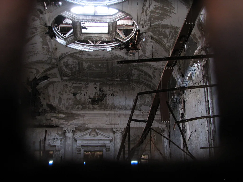 Ruined interior with peeling walls beneath a damaged oculus.