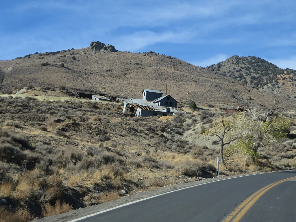 Cluster of deserted buildings with partly collapsed roofs on a dry hillside.