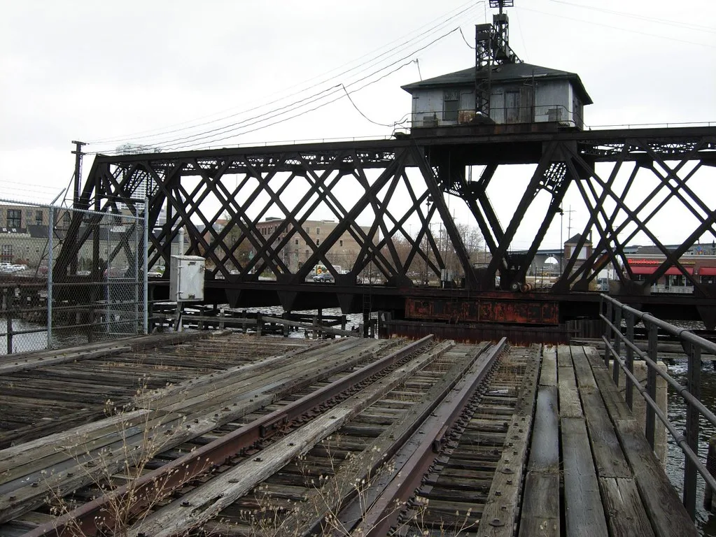 Old movable railway bridge beyond deteriorated tracks and decking.