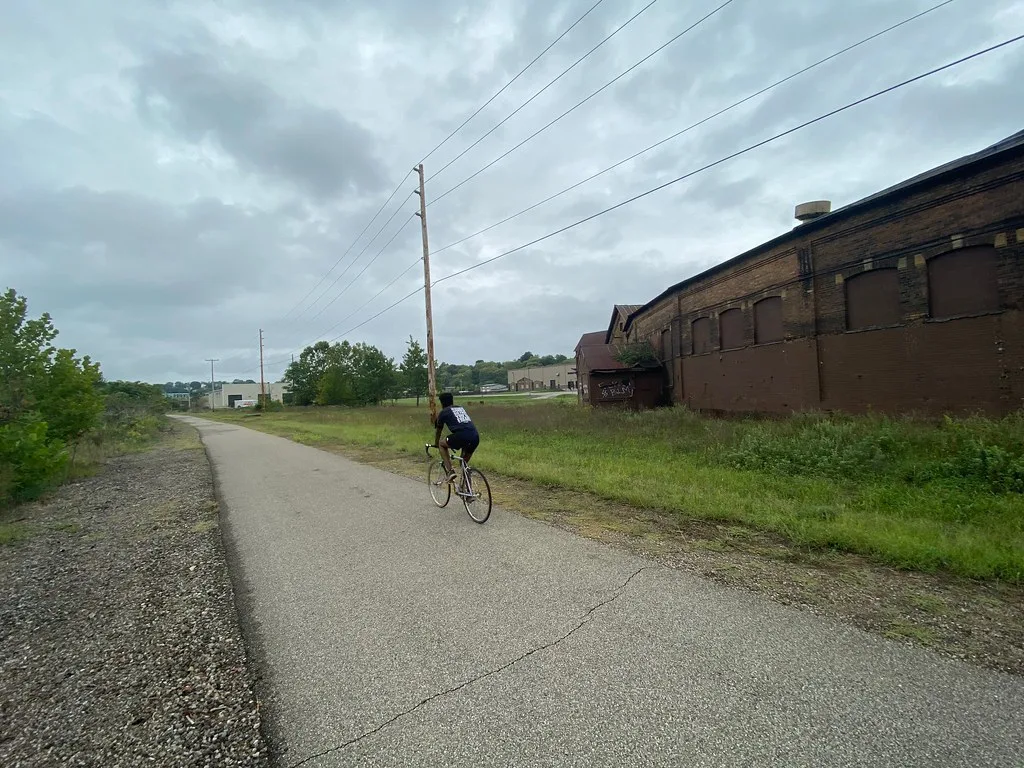 Old brick industrial building beside a path with a cyclist.