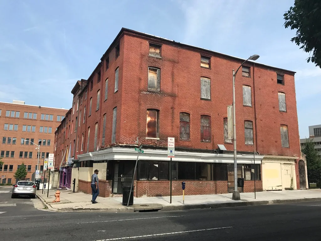 Large brick building with boarded windows at a street corner.