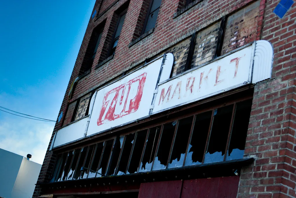 Old brick storefront with a faded sign and broken glass.