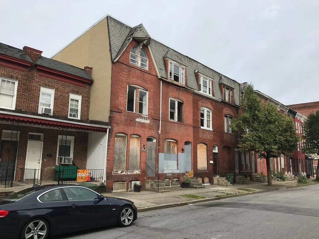 Brick houses with boarded openings along a street.