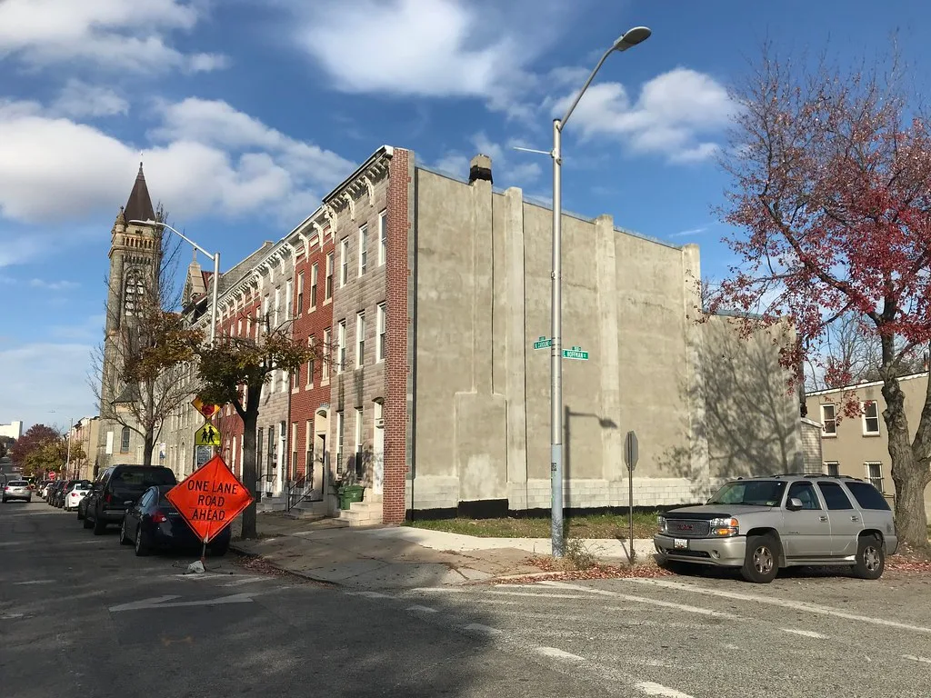 Exposed sidewall after demolition beside brick rowhouses in Baltimore