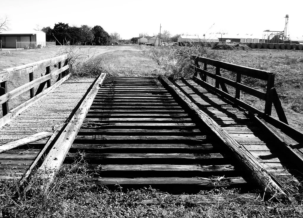 Disused railway bridge with damaged wooden sleepers and removed rails.