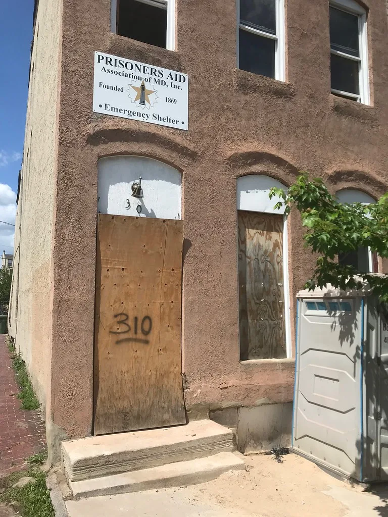 Old facade with boarded doors and ground-floor windows.