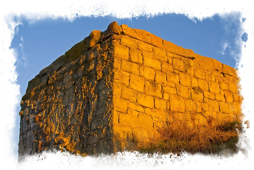 Stone wall remains in golden light, with a decorative white border.