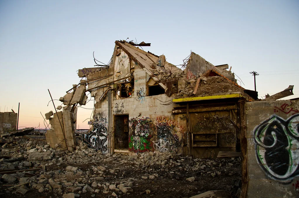 Graffiti-covered concrete ruin amid rubble.