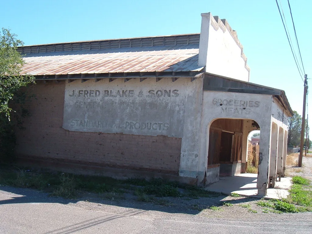 Closed old shop with a porch and a faded painted sign.