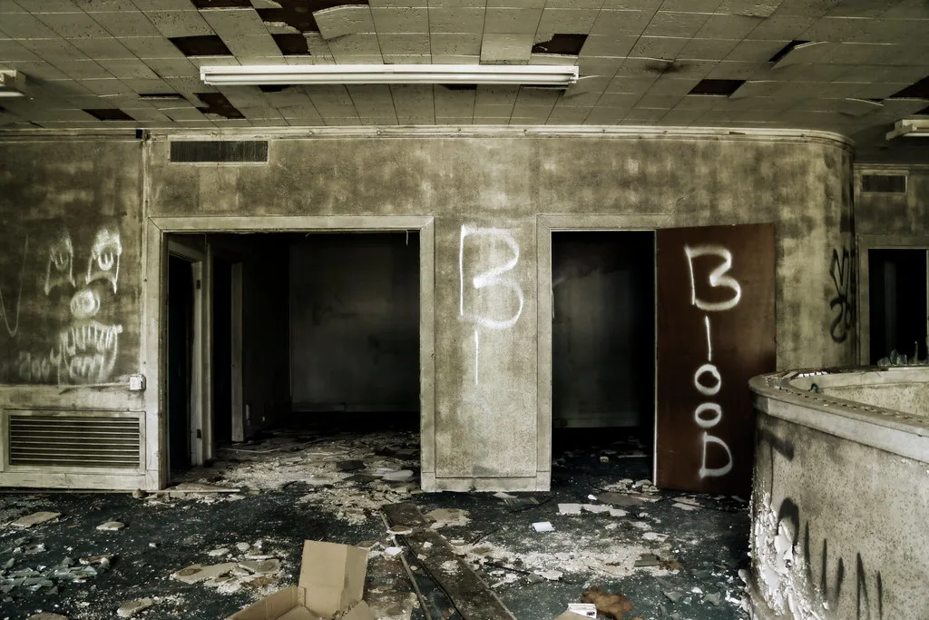 Deteriorated interior with open doorways and rubble-covered floor.